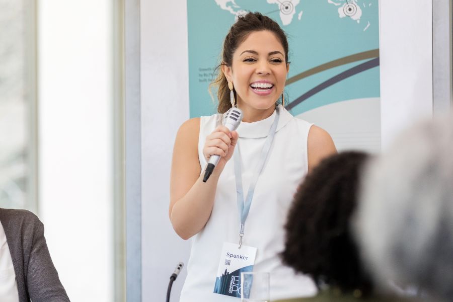 How to Choose the Best Conference Room Setup for Your Event 5 Conference speaker smiling woman giving presentation.